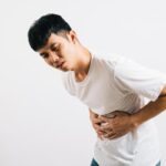 Man holding his upper abdomen in pain, which may be gastric pain or gallstones