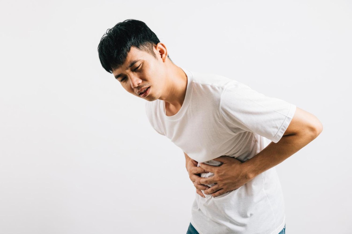 Man holding his upper abdomen in pain, which may be gastric pain or gallstones